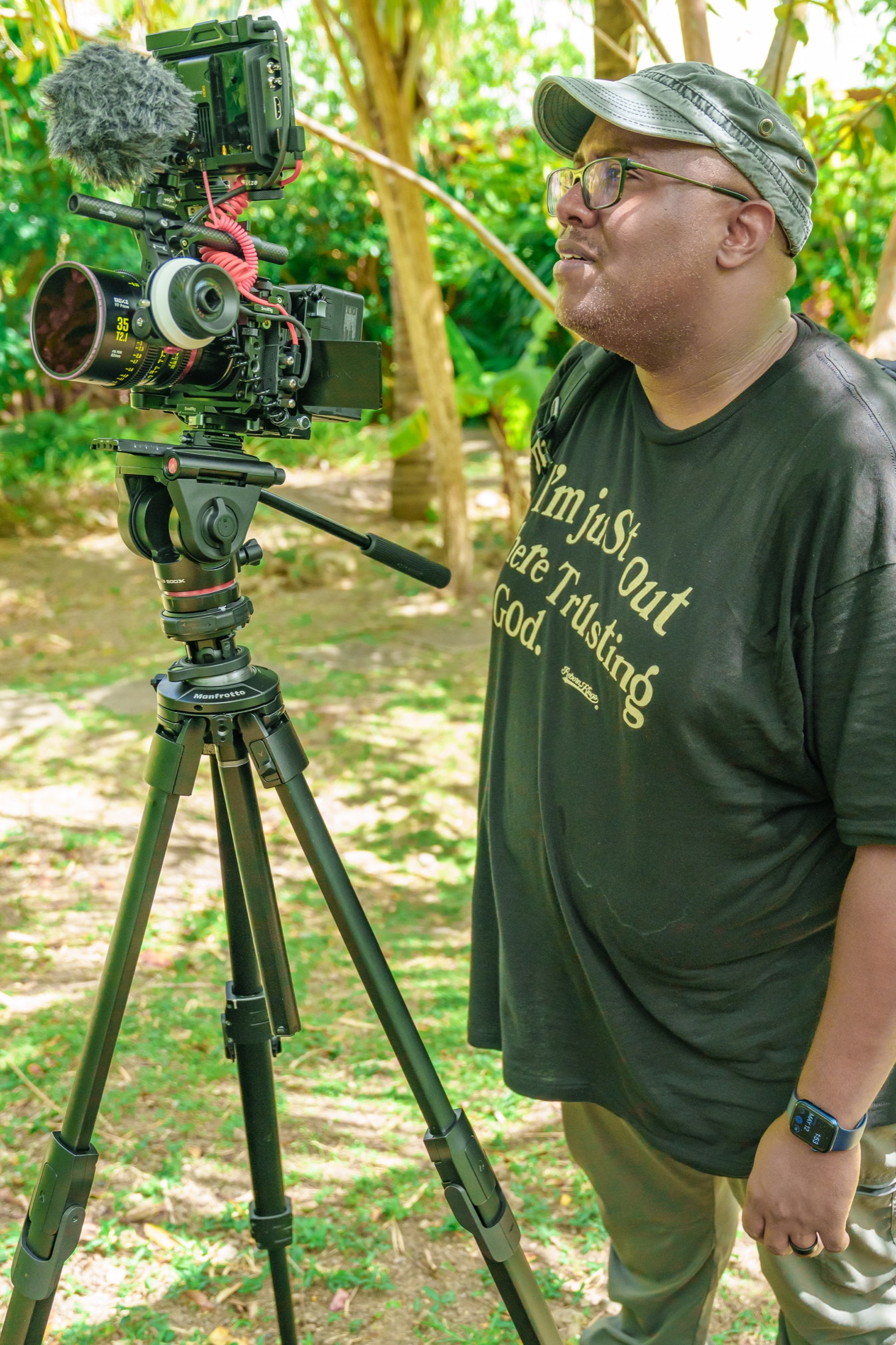 Thomas working beside his cinema camera in a tropical garden